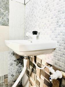 a bathroom with a white sink on a wall at Junglee tree stays in Hampi
