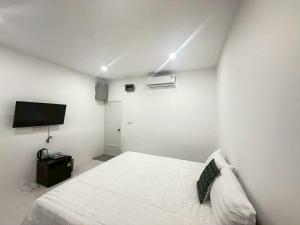 a white bedroom with a bed and a flat screen tv at DD Bangrak Hotel in Koh Samui