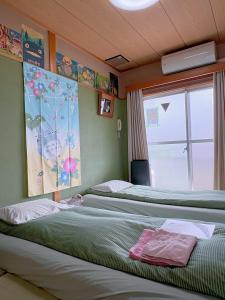 two beds in a room with a window at Direct to Shinjuku 15 mins Up to 6Guests in Tokyo