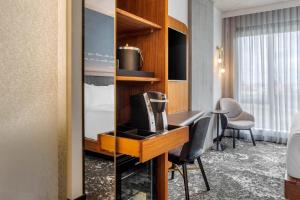 a hotel room with a desk with a television and a bed at Cambria Hotel Boston Downtown - Seaport in Boston