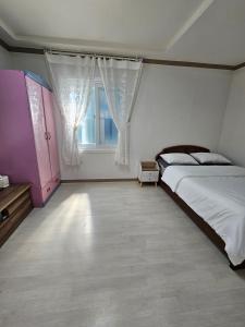 a bedroom with a large bed and a window at Gwangalli Tahee House in Busan