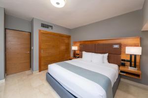 a bedroom with a large white bed and wooden doors at Radisson Hotel Santo Domingo in Santo Domingo +54 photos