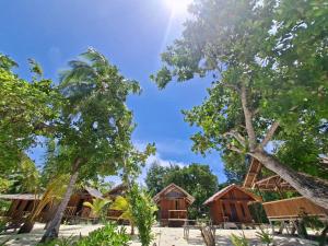 a group of houses on the beach with trees at Cozzy Saukabu Homestay in Fam