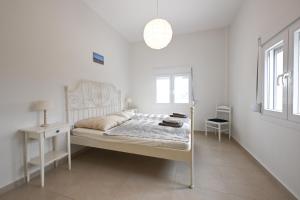 a white bedroom with a white bed and a lamp at Palataki in Epanomi