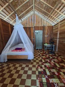 a bedroom with a bed with a mosquito net at Cozzy Saukabu Homestay in Fam