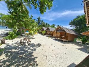 a row of huts on a beach with trees at Cozzy Saukabu Homestay in Fam