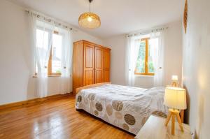a bedroom with a bed and two windows and a lamp at Les pinsons in Parques