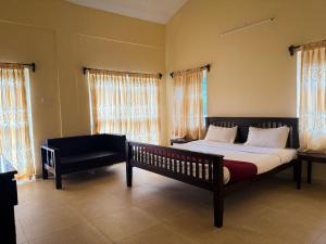 a bedroom with a bed and a couch and windows at The Temple Tree Residence in Yelagiri