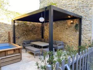 a patio with a table and chairs under a black canopy at La Romance de Grignan in Grignan