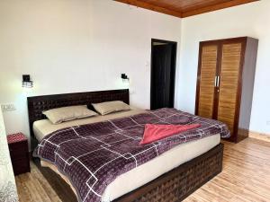 a bedroom with a bed with a red towel on it at AtulyaNeer Lakeview Cottage in Kanatal