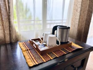 a wooden tray with two cups and a coffee maker on a table at AtulyaNeer Lakeview Cottage in Kanatal