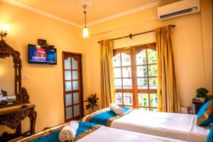 a bedroom with two beds and a tv on the wall at Hotel Seagull in Calangute +41 photos