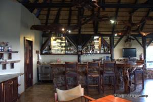 a bar in a restaurant with wooden tables and chairs at Mondjila Safari Camp in Okaukuejo