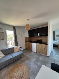 a living room with a couch and a kitchen at Appartement T2 moderne - Résidence Lecci - Piscines & proche Mer in Lecci