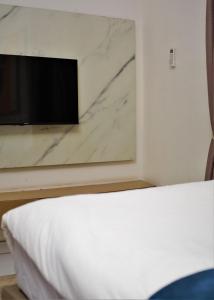 a bed in a room with a tv on a wall at Top city Homes in Lagos