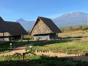 two huts in a field with a mountain in the background at AMBOKILI COTTAGES AMBOSELi in Nairobi