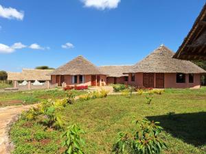 a house with thatched roofs in a yard at AMBOKILI COTTAGES AMBOSELi in Nairobi