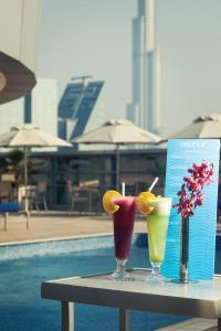 three cocktails on a table next to a pool at Carlton Downtown Hotel in Dubai