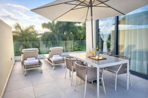 a patio with a white table and chairs and an umbrella at Dream House Las Terrenas Terraza privada & Jacuzzi in Las Terrenas