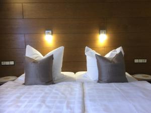 a bed with white pillows in a hotel room at Bergquell Tirol in Jungholz