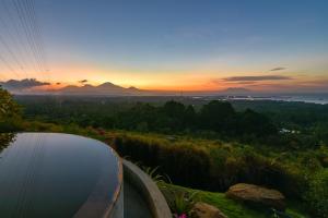 a pool of water with the sunset in the background at Sumberkima Resort in Pemuteran
