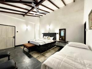 a bedroom with two beds and a ceiling at Shvaas Boutique Villa in Dambawelagama +10 photos