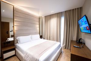 a hotel room with a bed and a flat screen tv at Duka's Boutique Hotel in Ksamil