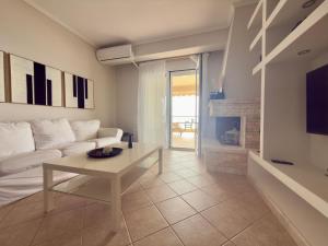a living room with a white couch and a table at Remvi Beachfront Suites by Horizon Homes in Orfánion