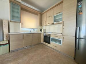 a kitchen with wooden cabinets and a stainless steel refrigerator at Remvi Beachfront Suites by Horizon Homes in Orfánion