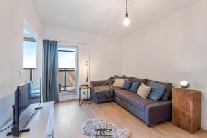 a living room with a couch and a tv at Sandy View - spacious studio flat near the beach in Nieuwpoort