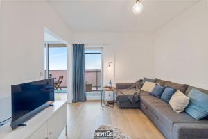 a living room with a couch and a tv at Sandy View - spacious studio flat near the beach in Nieuwpoort