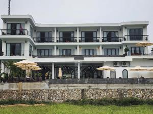 a large white building with umbrellas in front of it at Karst Residence Phong Nha in Phong Nha