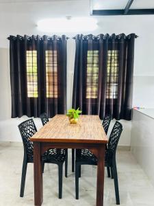 a dining room table with chairs and black curtains at Mausam Homestay in Sultan Bathery