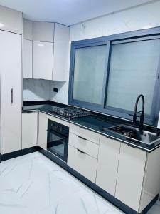 a kitchen with white cabinets and a stove and a sink at Apartamento Muy Lempio Organizado y Tranquilo in Nador