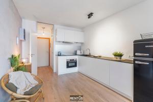 a kitchen with white cabinets and a black refrigerator at Sandy View - spacious studio flat near the beach in Nieuwpoort +16 photos