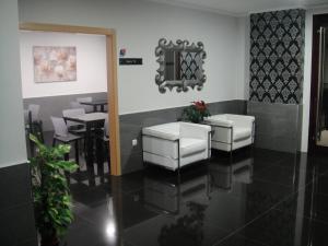 a dining room with white chairs and a mirror at Aparthotel El Faro in Cullera