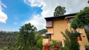 a house on a hill with trees in the background at Natural Elements by Levitate - Premium Two Room Chalet with Private Terrace Panoramic Forest View & Dedicated Kitchen in Rāmgarh