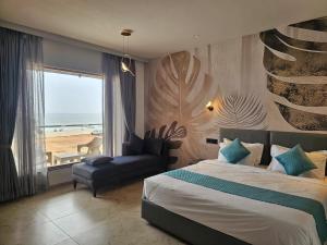 a bedroom with a bed and a chair and a window at Le Sparrow Beach- Rooms in Mangalore