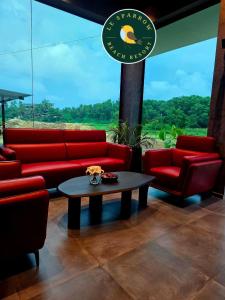 a living room with red couches and a coffee table at Le Sparrow Beach- Rooms in Mangalore