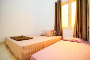 two beds in a room with a window at Rayyan Homestay Jogja in Timuran