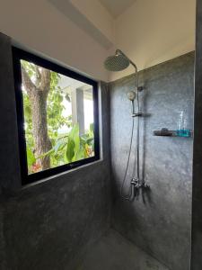 a shower in a bathroom with a window at Lara's place in Unawatuna