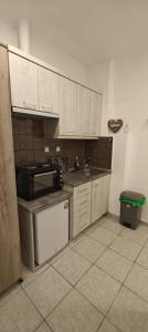 a kitchen with white cabinets and a sink and a stove at Melirito in Olympiada