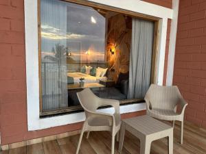 a balcony with two chairs and a window with a bedroom at Le Sparrow Beach- Rooms in Mangalore