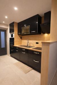 a kitchen with black cabinets and a sink at Maison cosy proche plage in Elne