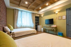 a room with two beds and a television in it at 羅東夜市舒果ShuGo B&B 近清溝夜市 國旅卡特約店 配合租車行 in Luodong