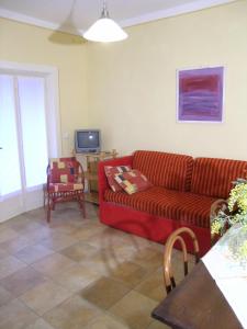 a living room with a red couch and a tv at L'oleandra appartamenti in Lacona