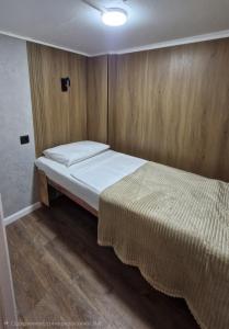 a small bedroom with a bed and wooden walls at Hostel CAPS HOME boutique in Astana +15 photos