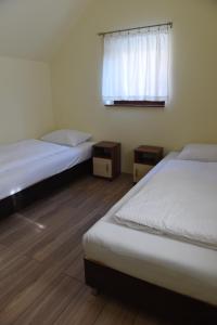2 Betten in einem Zimmer mit Fenster und Holzböden in der Unterkunft aQuarium Panzió in Abádszalók