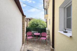 a patio with three chairs and a pink table at Къщата с чешмата in Veliko Tŭrnovo