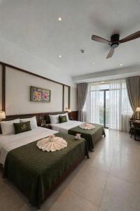two beds in a bedroom with a ceiling fan at Magnolia Boutique Hue in Thôn Trường Giang